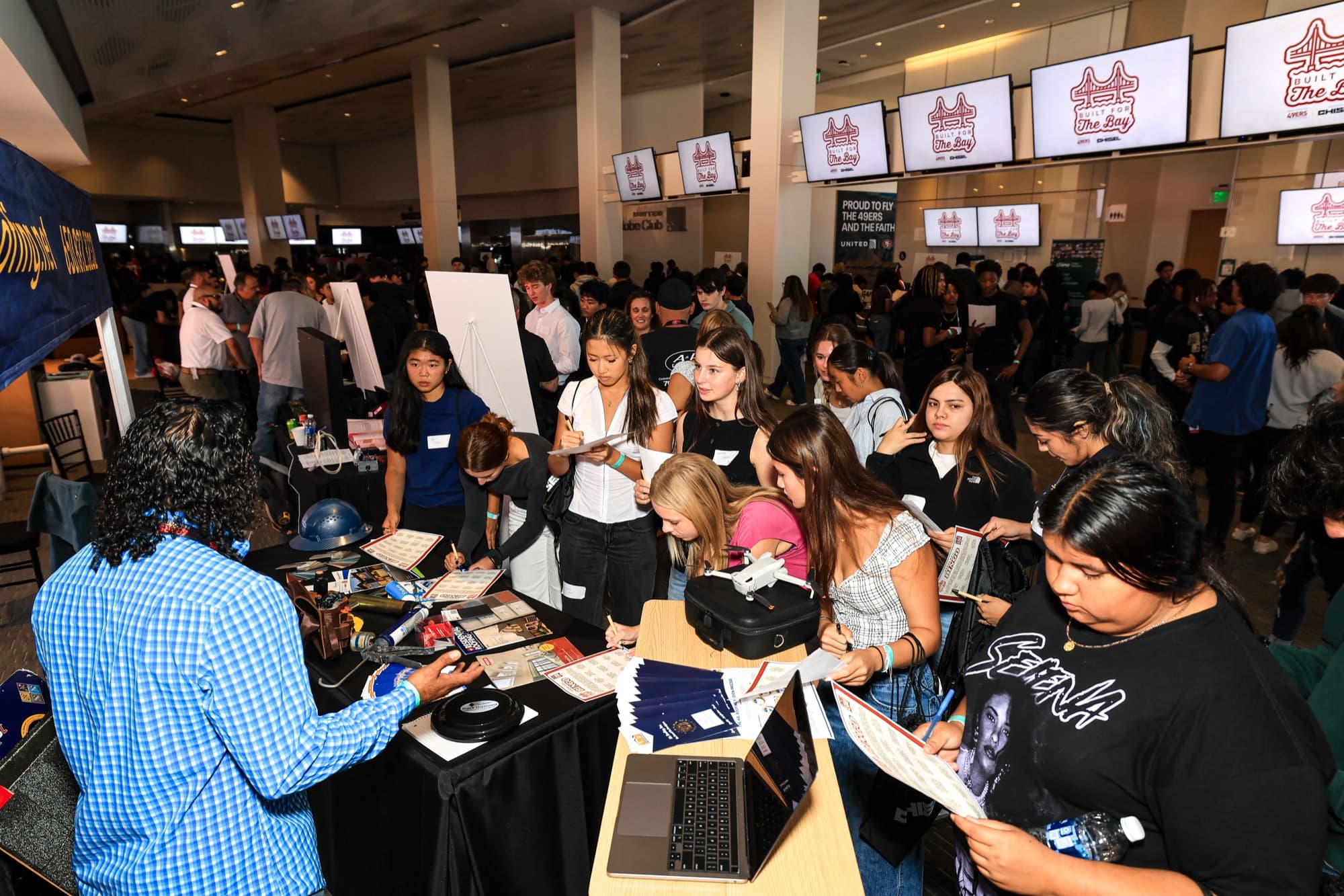 Students crowd around trades company tables inside Levi's Stadium at Built for the Bay